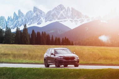 Arka planda manzaralı kırsal bir yolda giden şık siyah SUV.