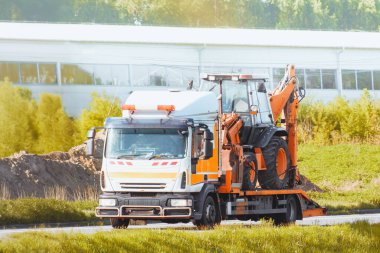 Güneşli bir yaz gününde, otoyolda mini kazıcılı bir çekici.