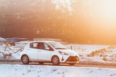 Kış yolunda beyaz araba sürüyor.