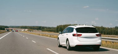 Otoyol boyunca giden beyaz Combi arabası.