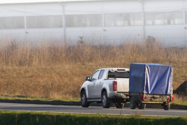 Trailer attached to car on scenic sunny road clipart