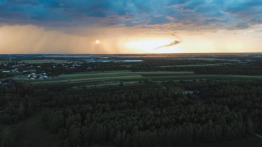 Uğursuz günbatımı gökyüzünün altında tarım arazileri ve ormanlar