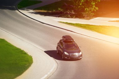 Şehir yolunda çatı kargo kutusu olan aile arabası.