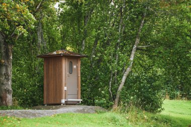 Kalabalık orman ağaçlarının arasında umumi tuvalet.