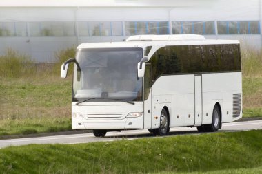 Kırsal yolda giden büyük beyaz bir otobüs.