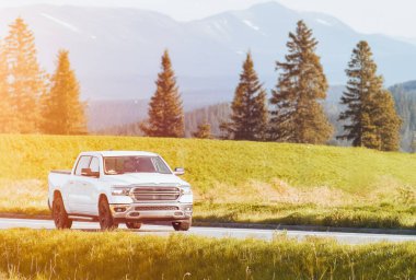 Kırsal yolda giden beyaz bir kamyonet.