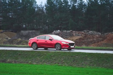 Kırsal kesimde hızla giden kırmızı bir araba.