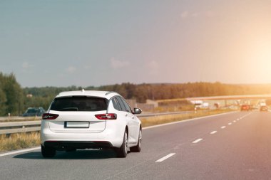 Otoyol boyunca giden beyaz Combi arabası.