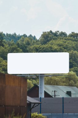 Empty roadside billboard with blank space and trees in background clipart