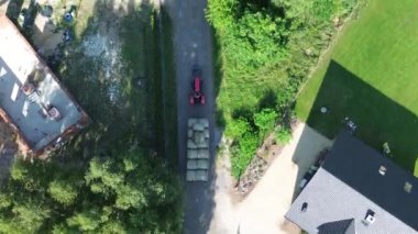 Geniş yeşil bir tarlanın tepesinde, bir sürü ağaç ve çimen olan küçük bir kamyonun havadan görüntüsü.