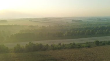 Güneşin doğuşu sisli tarlaları ve dağ yamaçlarını aydınlatıyor.