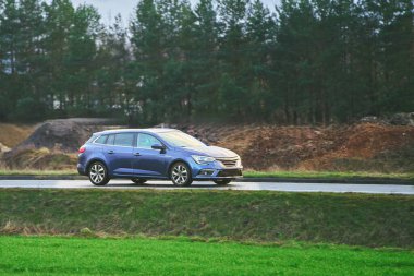 Ağaçlık arka planı olan mavi bir araba.