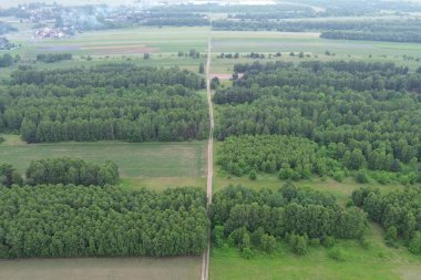 Toprak yol tarlalardan ve ormanlardan geçiyor.