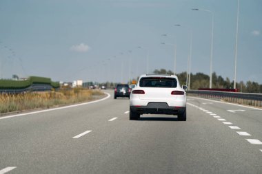 Rear view of white car on highway. clipart