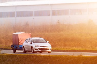 Güneşli kırsal yolda beyaz araba çekici römorku