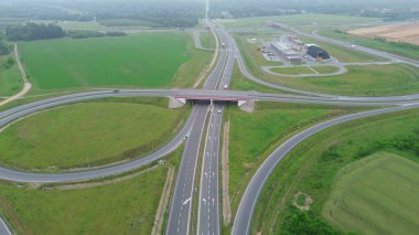 Arabalar ve yeşil manzaralı kırsal otoyol kavşağının yüksek görüntüsü