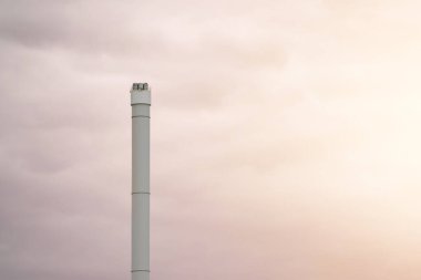Bulutlu gökyüzünün ortasında uzun bir baca yığını
