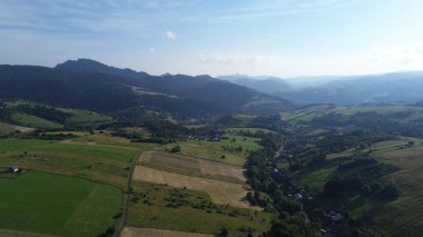 Yumuşak günbatımı ışığında yeşil tarlalar ve dağ sıraları