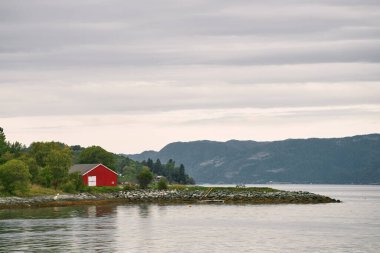 Norveç 'te gölün kıyısındaki büyüleyici kırmızı kulübe