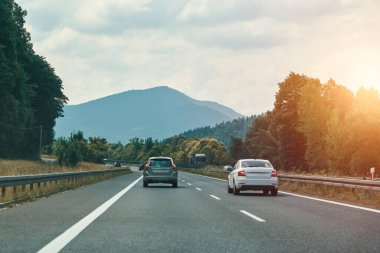Otoyolda dağlar olan arabalar hareket ediyor.