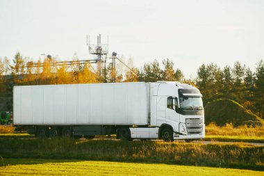 Kırsal yolda beyaz kamyon sürüyor.