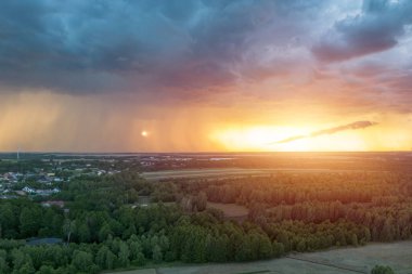 Şehir ve kırsal alanda gün batımında dramatik bir gökyüzü.