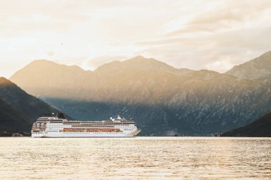 Gün batımında dağlara yakın büyük bir yolcu gemisi.
