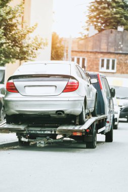 Şehir sokağında gümüş araba taşıyan çekici.