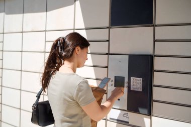 Kadın teslimat dolabında paket topluyor.