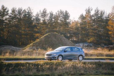 Kırsal alanda modern hatchback araba sürüyor.