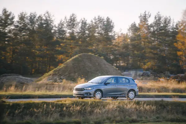 Kırsal alanda modern hatchback araba sürüyor.