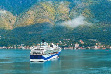 Bulutlu gökyüzünün altında Kotor Körfezi 'nde lüks bir yolcu gemisi.