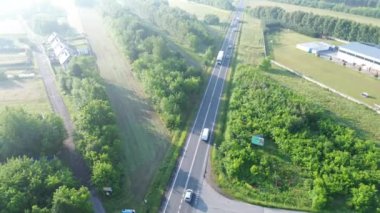 Kırsal bir otoyolda beyaz teslimat kamyonu sürüyor.