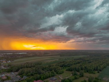 Uğursuz günbatımı gökyüzünün altında tarım arazileri ve ormanlar