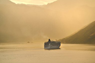 Sisli dağın yanından geçen bir yolcu gemisi.