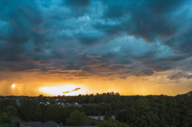 Şehir ve kırsal alanda gün batımında dramatik bir gökyüzü.
