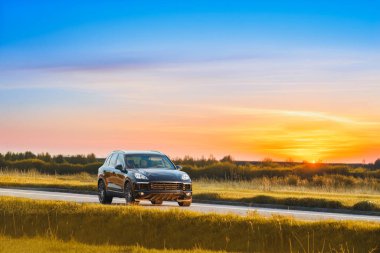 Siyah Alman SUV gün batımında bir kır yolunda gidiyor.