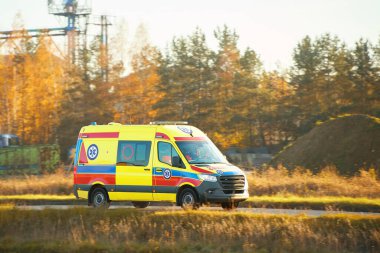 Sanayi bölgesi yakınlarında sarı ambulans sürüyor.