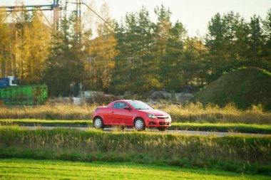 Kırsal yolda ilerleyen kırmızı araba.