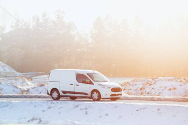 Karlı yolda giden beyaz minibüs.