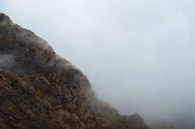 Durgun göl yüzeyinde sislerle kaplı dağlar