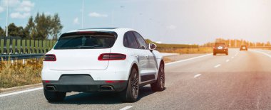 Parlak güneşli bir otoyolda beyaz bir araç..