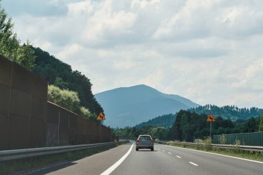 Araçlar bulutlu gökyüzünün altında otoyolda ilerliyor