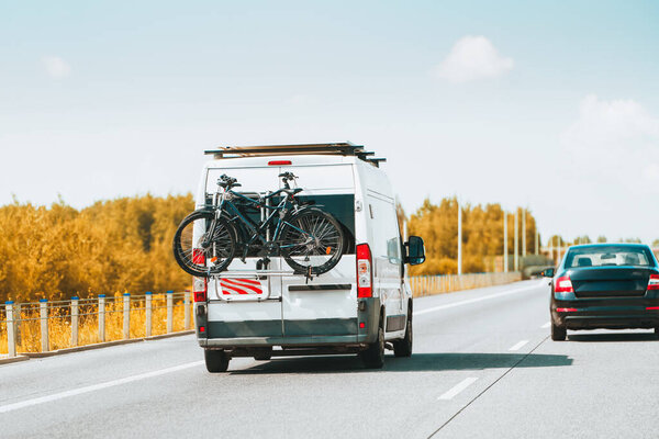Camper van driving on highway with bikes