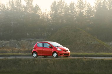 Modern kırmızı hatchback açık havada sürüyor.
