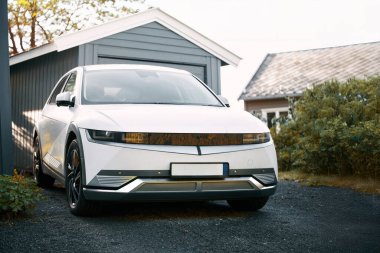 Banliyö bölgesinde park etmiş parlak beyaz elektrikli cip manzarası.