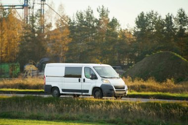 White commercial van on countryside road clipart