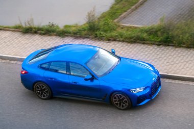 Lüks mavi araba kaldırım kenarında sürüyor.