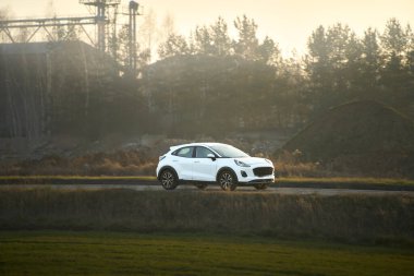 Kırsal alanda dolaşan beyaz elektrikli araba.