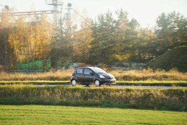 Kırsal alanda modern hatchback araba sürüyor.